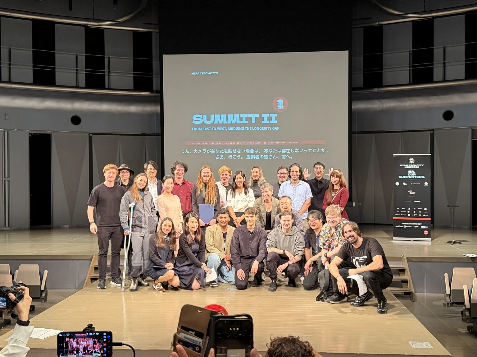 Participants gathered on stage beneath the Summit II screen at MIRAI TECH CITY in Kobe