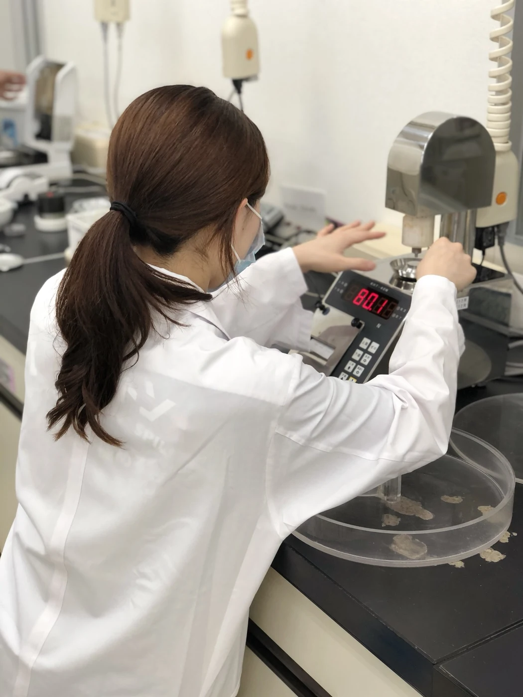 A laboratory specialist handling a sample on a benchtop instrument